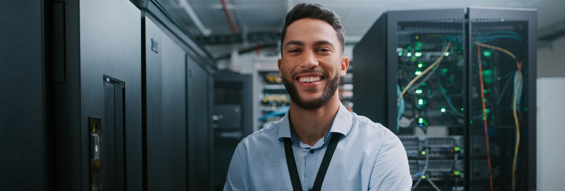IT professional standing in a server room with rack-mounted UPS systems and network equipment ensuring business continuity.